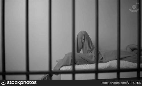Black and white A suicidal inmate in prison laying on bed