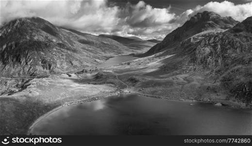 Black and white Aerial view of flying drone Epic early Autumn Fall landscape image of view along Ogwen vslley in Snowdonia National Park with dramatic sky and mountains