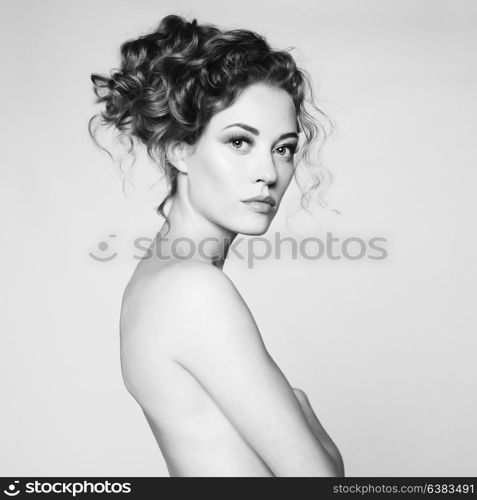 Black and white art portrait of sensual nude woman with elegant hairstyle on gray background