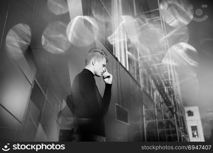 Black and white artistic photography. Young blonde man standing on street. Black and white artistic photography. Young blonde man in black wear standing on street.