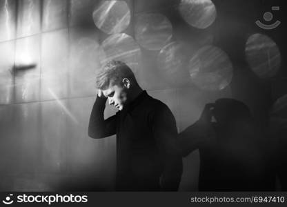 Black and white artistic photography. Young blonde man standing on street. Black and white artistic photography. Young blonde man in black wear standing on street.