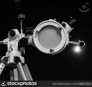 Black and white Astronomical telescope. Astronomical telescope over dark sky with the moon - selective focus on telescope in black and white
