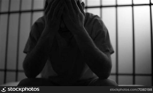 Black and white Backlit scene of a depressed inmate in prison