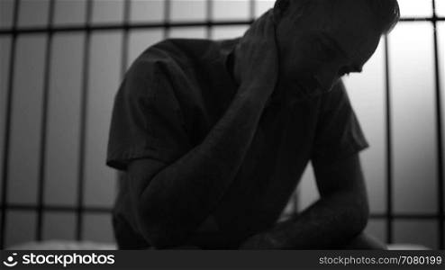 Black and white Backlit scene of a despondent inmate in prison