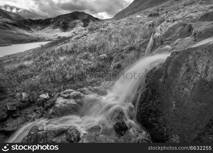Black and white Beautiful landscape image of stream near Llyn Ogwen in Snowdonia during early Autumn flowing towards Tryfan in background