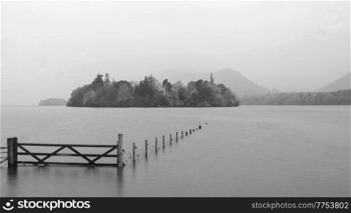 Black and white Beautiful long exposure landscape image of Derwentwater looking towards Catbells peak in Autumn during early morning