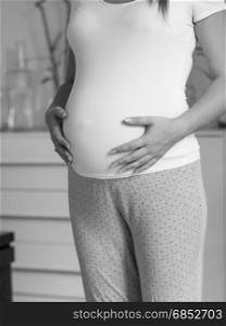 Black and white beautiful pregnant woman in white t-shirt touching big belly