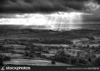 Black and white beautiful sunbeams over Big Moor in the Peak Dis. England, Derbyshire, Curbar Edge. Sunbeams over Big Moor in the Peak District in Autumn.. Stunning black and white sunbeams over Big Moor in the Peak District landscape in Autumn
