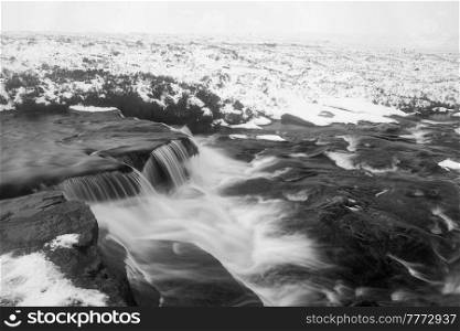 Black and white Beautiful Winter landscape image of River Etive in foreground with iconic snowcapped Stob Dearg Buachaille Etive Mor mountain in the background
