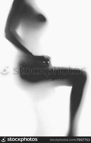 Black and white blurred photo of sexy naked woman putting on nylon stockings