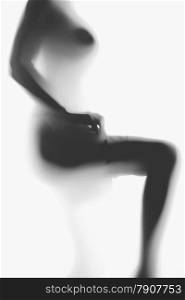 Black and white blurred photo of sexy naked woman putting on nylon stockings