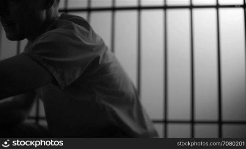 Black and white Close-up dolly shot of a depressed inmate in prison