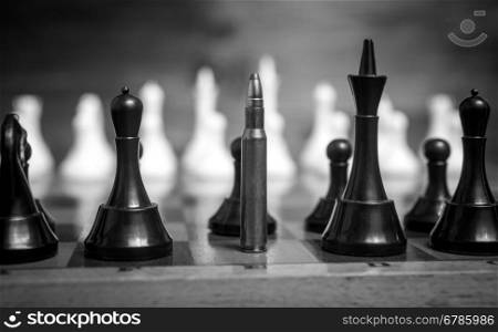 Black and white closeup photo of bullet in row of chess pieces
