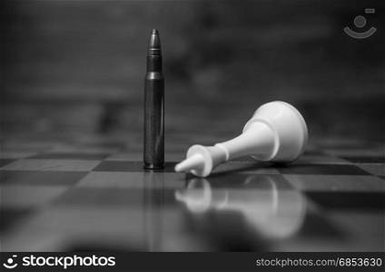 Black and white closeup photo of bullet wins chess game. Concept of gun power