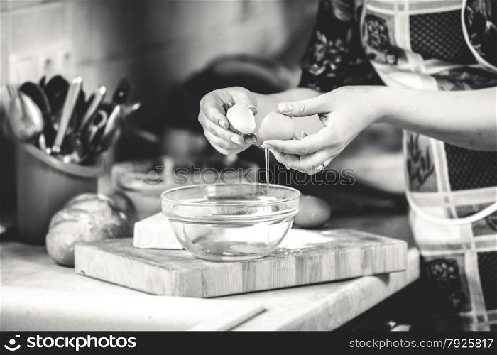 Black and white closeup photo of woman cracking egg