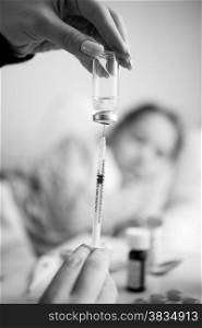 Black and white closeup photo of woman filling syringe from ampule
