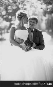 Black and white closeup portrait of happy bride and groom kissing under big tree