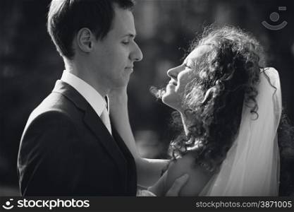 Black and white closeup portrait of happy bride and groom looking at each other