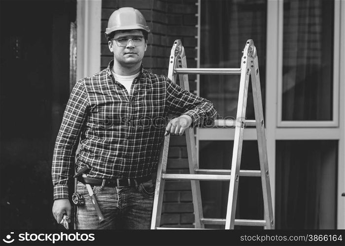 Black and white closeup portrait of professional worker posing with metal ladder