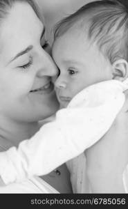 Black and white closeup portrait of smiling mother holding her baby boy