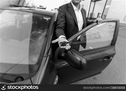 Black and white closeup shot of car sales manager holding key on hand