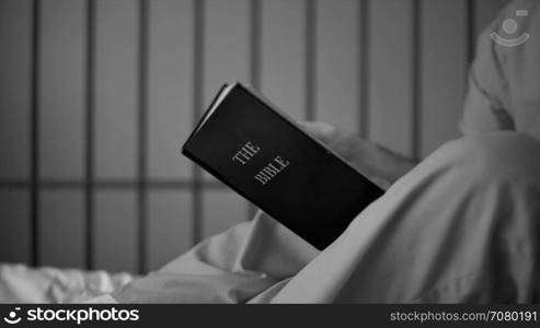 Black and white dolly shot of an inmate reading scriptures in prison