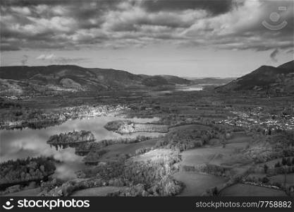 Black and white Epic landscape Autumn image of view from Walla Crag in Lake District, over Derwentwater looking towards Catbells and distant mountains with stunning Fall colors and light