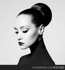 Black and white fashion art studio portrait of beautiful elegant woman in black turtleneck. Hair is collected in high beam. Elegant ballet style