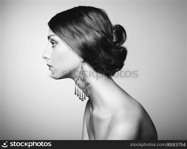Black and white fashion art studio portrait. Photo of beautiful young woman with earring. Elegant Hairstyle