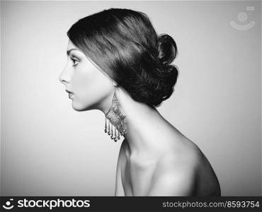 Black and white fashion art studio portrait. Photo of beautiful young woman with earring. Elegant Hairstyle