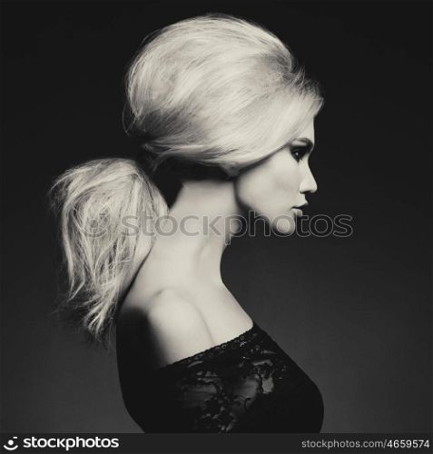 Black and white fashion studio portrait of beautiful blonde woman with elegant hairstyle on black background