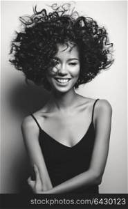 Black and white fashion studio portrait of beautiful woman in black dress with afro curls hairstyle. Fashion and beauty