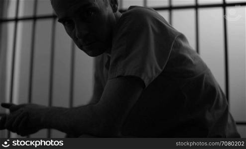 Black and white frustrated Inmate stares at camera in a jail or prison