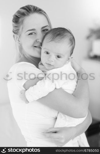 Black and white image of cheerful young mother hugging her baby boy