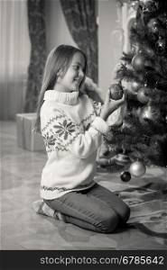 Black and white image of happy smiling girl decorating Christmas tree