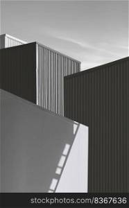 Black and white image of light and shadow on cold storage room surface with corrugated metal industrial buildings in perspective view and vertical frame