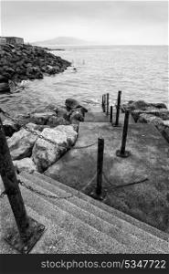 Black and white image of old steps leading down into sea