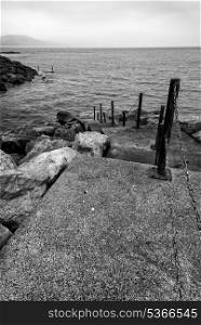 Black and white image of old steps leading down into sea