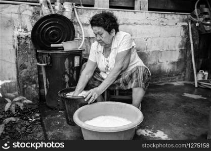 Black and white image of Senior asian woman washing cloths by hand