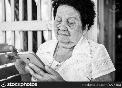 Black and white image of Senior asian woman with smart phone