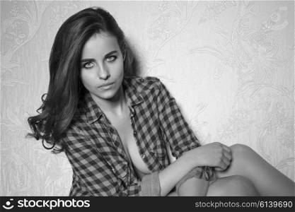 black and white image portrait of stunning brunette woman with unbuttoned plaid shirt, long hair and make-up. She is looking in camera