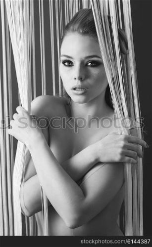 black and white , images , indoor portrait of sexy woman with freckles, nude body and stylish make-up. She is covering her breast and looking in camera