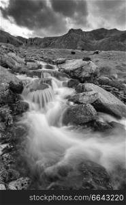 Black and white Landscape image of river flowing down mountain range near Llyn Ogwen and Llyn Idwal in Snowdonia in Autumn
