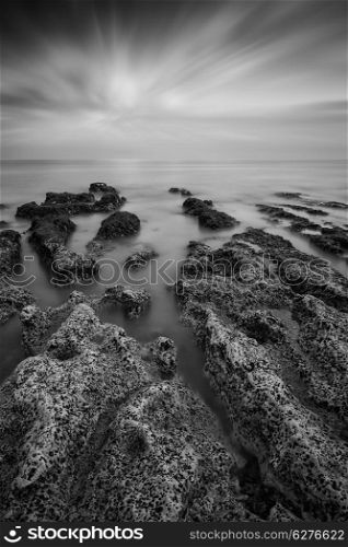 Black and white landscape looking out to sea with rocky coastline and beautful sunset sky
