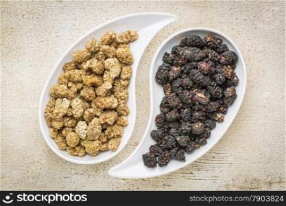 black and white mulberry - sun-dried fruit on teardrop shaped bowls against rustic barn wood