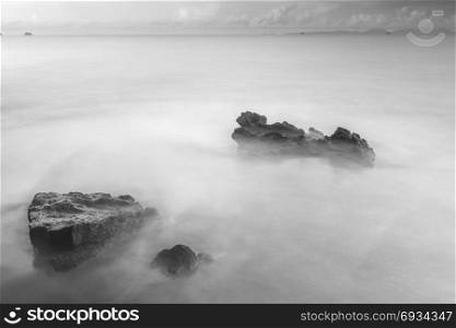 black and white mystical photo - sea waves and cobblestones on the beach close up