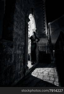 Black and white night photo of sexy woman posing at old arch