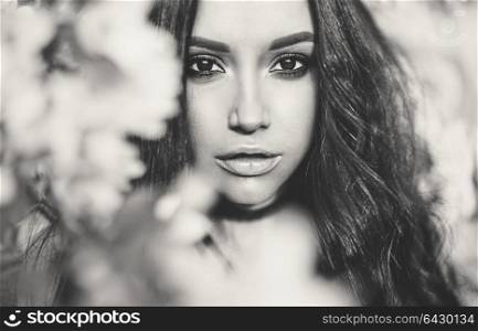 Black and white outdoor fashion photo of beautiful young woman surrounded by flowers of apple-tree. Spring blossom