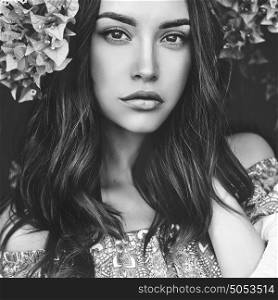 Black and white Outdoor fashion photo of beautiful young woman surrounded by flowers