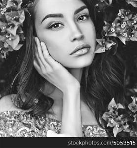 Black and white Outdoor fashion photo of beautiful young woman surrounded by flowers